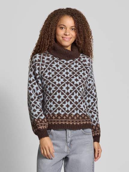 Frauenmodel trägt Rollkragenpullover mit Ballonärmeln von ONLY in Jacquard-Strick, mehrfarbig, geometrisches Allover-Muster, Ganzkörperansicht von vorne.
