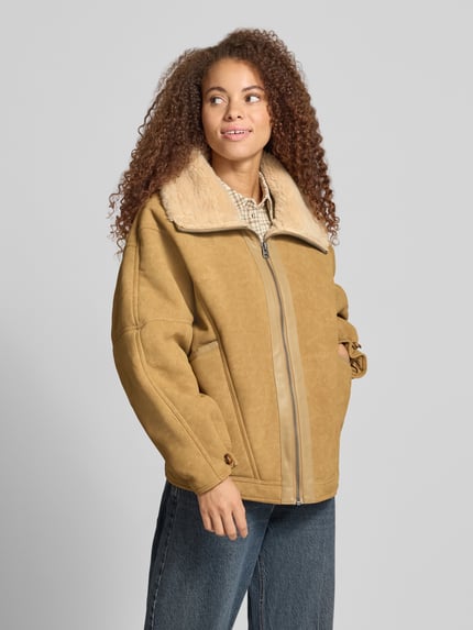 Frauenmodel trägt Kunstlederjacke mit Teddykragen von [Marke], beige Töne, weiche Struktur, Rückenlänge S: 66 cm, Ganzkörperansicht von vorne.