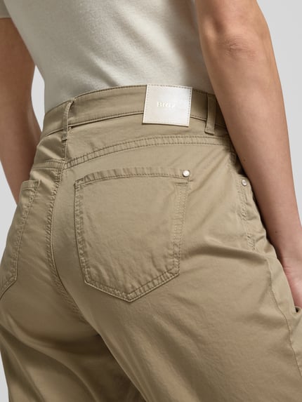 Vrouwenmodel draagt Hose mit Eingrifftaschen Modell 'Carola' van Brax in beige, mix van katoen en lyocell, regular fit, bandwijdte 39 cm, binnenbeenlengte 76 cm, steekzakken, detailopname rugaanzicht.