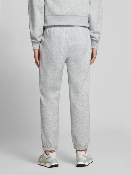 Mannenmodel draagt grijze sweatpants met labelstitching Model 'ICONS' van Champion, katoenmix, recht model, elastische band, steekzakken, binnenbeenlengte maat M 76 cm, volledige lichaamsweergave achterkant.