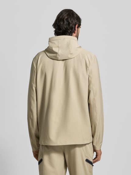 Męski model nosi Regular Fit Jacke mit Logo-Print Modell 'Unstoppable' von Under Armour, elastyczna mieszanka materiałów, krój regular fit, logo-print, wpuszczane kieszenie zapinane na zamek błyskawiczny, zamek błyskawiczny, kaptur ze stójką, długość tyłu w rozmiarze M: 74 cm, długość rękawów w rozmiarze M: 68 cm, kolor beżowy, gładka tekstura, widok całej sylwetki z tyłu.