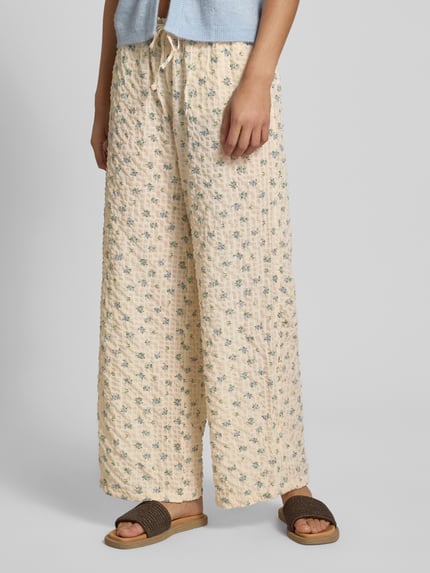 Frauenmodel trägt Wide Leg Pull-on-Hose aus Seersucker mit Kordelzug von REVIEW, Elastischer-Material-Mix, creme mit Blumenmuster, Nahaufnahme Unterkörper, Ganzkörperansicht von vorne.