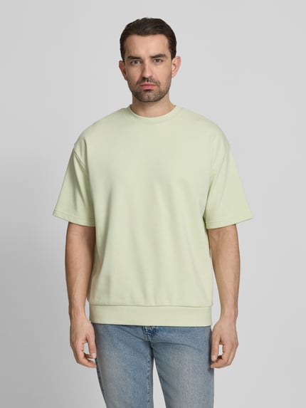 Männermodel trägt Oversized T-Shirt mit Rundhalsausschnitt von Lindbergh aus Baumwoll-Mix, Label-Detail, Rückenlänge 70 cm, Ganzkörperansicht von vorne.