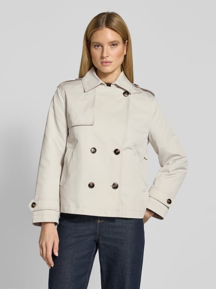 Modelka kobieca nosi Trenchcoat in kurzem Design mit Baumwoll-Anteil von Jake*s Casual, jasnobeżowy, bawełniany materiał, prosta forma, kołnierz, podwójny rząd guzików, kieszenie, pagony, krótki krój, szerokość w rozmiarze 36: 44 cm, długość 64 cm, szerokość klatki 51 cm, długość rękawa 60 cm, widok całej sylwetki z przodu
