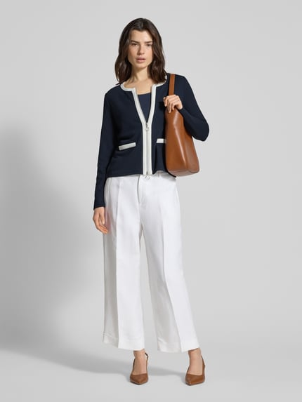 Vrouwenmodel draagt Slim Fit Jacke mit Viskose-Anteil in tricotlook van Betty Barclay, donkerblauw met witte accenten, Ganzkörperansicht von vorne. Ruglengte maat 36: 54 cm, elastische materiaalmix, ronde hals, tweewegritssluiting, klepzakken.