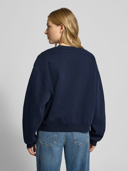 Vrouwenmodel draagt Relaxed Fit Sweatshirt uit katoenmix van Tommy Hilfiger in effen donkerblauw, geribde boorden, label stitching, volledig achteraanzicht.