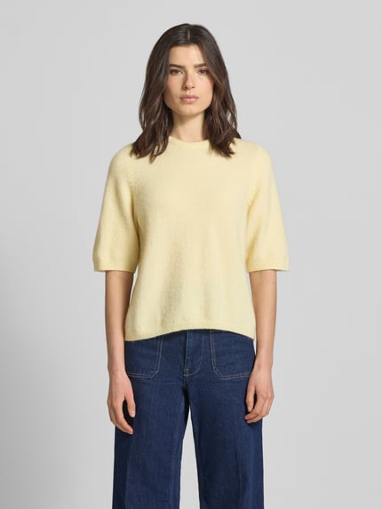 Frauenmodel trägt Relaxed Fit T-Shirt aus Alpaka-Mix Modell 'Alpha' von Gestuz, elastischer Alpaka-Mix mit Escorial-Woll-Anteil, Damen T-Shirt in zartem Gelb, Strick-Optik, Halbarm, Rundhalsausschnitt, elastische Abschlüsse, Rückenlänge 56 cm, Ärmellänge 34 cm, Ganzkörperansicht von vorne.