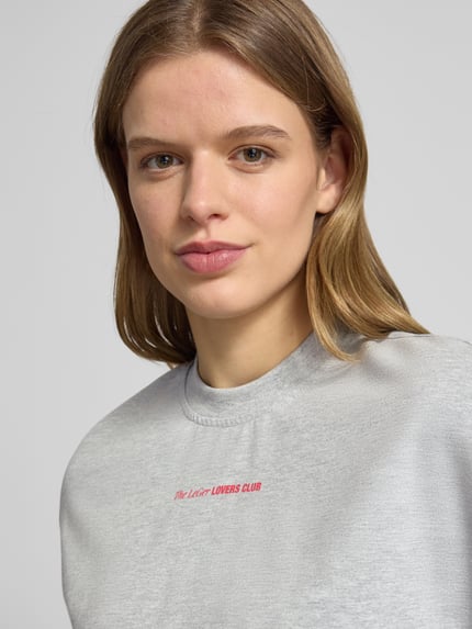 Frauenmodel trägt Oversized T-Shirt mit Rundhalsausschnitt Modell 'Lotte' von LeGer by Lena Gercke aus reiner Baumwolle, Label-Print, Nahaufnahme Oberkörper.
