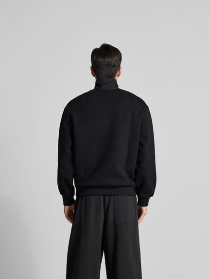 Męski model nosi troyer aus reiner Baumwolle von MAISON KITSUNÉ, kolor czarny, krój regular fit, detal z logo, brustasza, długość tyłu 68 cm, ganzkörperansicht rückansicht.