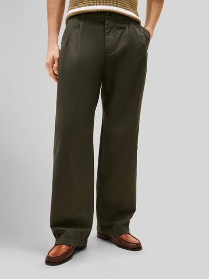 Männermodel trägt Loose Fit Hose mit Bundfalten von Tommy Hilfiger, Optik: Unifarben, Passform: Loose-Fit, reine Baumwolle, Ganzkörperansicht von vorne.