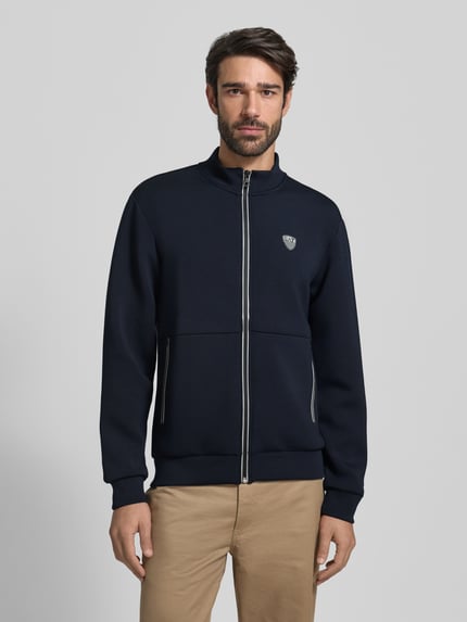 Männermodel trägt Sweatjacke mit Reißverschluss von EA7 Emporio Armani, Regular-Fit, Stehkragen, Label-Detail, Eingrifftaschen, dunkelblau, Vorderansicht, Nahaufnahme Oberkörper.