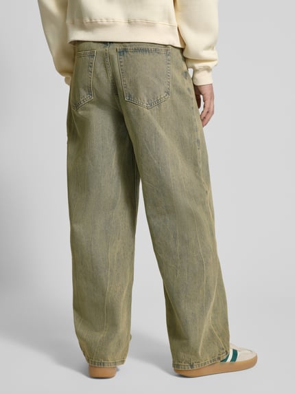 Męski model nosi Wide Fit Jeans mit Viskose-Anteil Modell 'Everyday' od ANOTHER COTTON LAB, bawełniany miks z domieszką wiskozy, fason wide fit, 5 kieszeni, kolor jasny niebieski z efektem sprania, zapięcie na guzik i zamek, szerokość w rozmiarze M: 37 cm, długość nogawki od wewnątrz w rozmiarze M: 29 cm, widok całej sylwetki od tyłu.