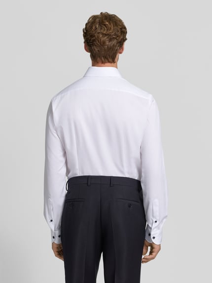 Männermodel trägt weißes Modern Fit Businesshemd mit extra langem Arm von OLYMP, glatte Struktur, Ganzkörperansicht Rückansicht, Herren Businesshemd von OLYMP.