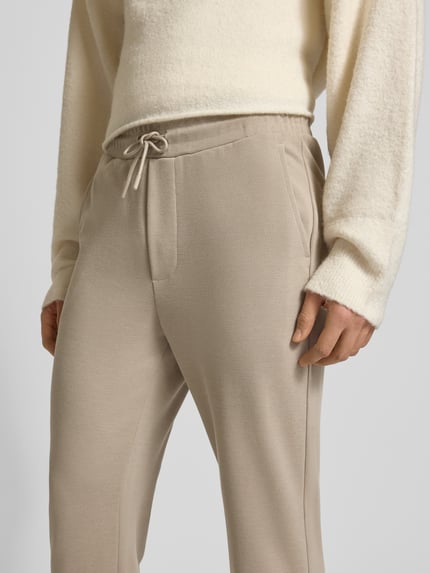 Männermodel trägt Regular Fit Stoffhose mit Tunnelzug Modell 'NEWKODYL LIFE LINUS' van Only & Sons in effen beige, zijzakken. Nahaufnahme Oberkörper.