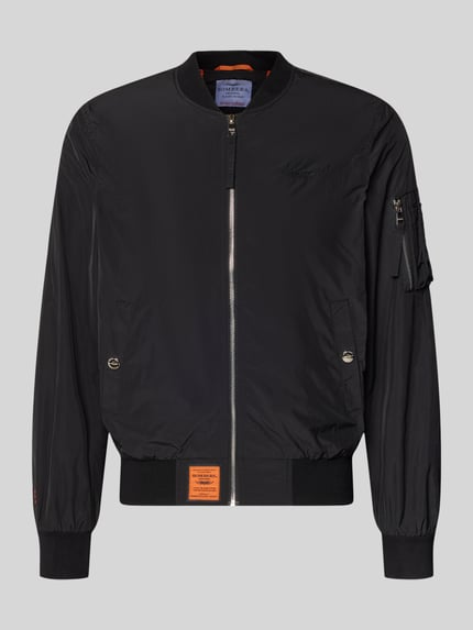 Produktfoto, Bomberjacke mit Label-Patch und Eingrifftaschen von Original Bombers in Schwarz mit Reißverschluss, Reißverschlusstasche am Ärmel, gerader Schnitt, gerippte Abschlüsse, Größenangaben für Herren.