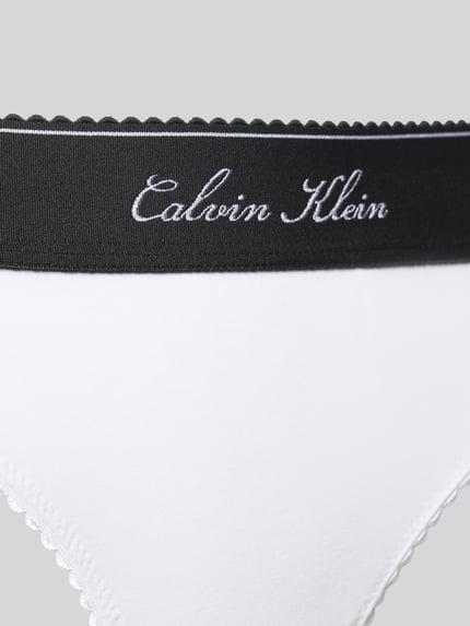 Frauenmodel trägt weißen String aus Baumwoll-Mix mit Modal-Anteil Modell 'SCRIPT Thong' von Calvin Klein Underwear, Nahaufnahme Oberkörper. Damen String von Calvin Klein Underwear.