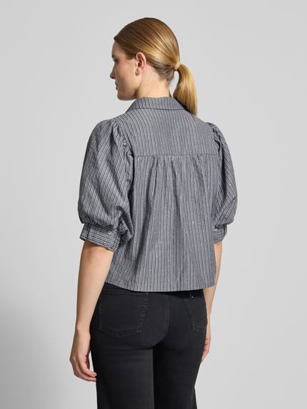 Frauenmodel trägt Bluse mit Puffärmeln Modell 'Etta' von Neo Noir, Kentkragen, Boxy Fit, feine Streifen, Rückenansicht, Nahaufnahme Oberkörper.