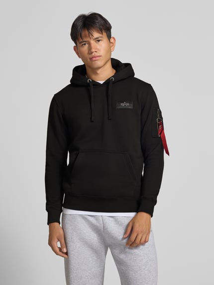 Männermodel trägt zwarte hoodie met kangoeroezak en labelprint, katoenmix, regular fit, Alpha Industries, voorkant, Nahaufnahme Oberkörper.