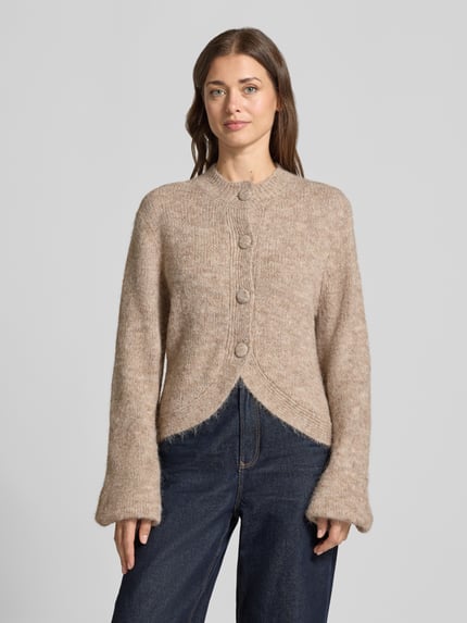 Frauenmodel trägt Strickjacke mit Stehkragen Modell 'Gio Fluffy' von Neo Noir, beige meliert, grobe Struktur, Regular Fit, Knopfleiste, Nahaufnahme Oberkörper. Damen Strickjacke Material-Mix mit Baumwoll-Anteil, Rückenlänge 55 cm, Ärmellänge 70 cm.