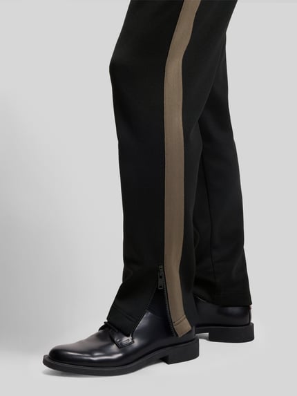 Männermodel trägt Relaxed Fit Jogginghose mit Galonstreifen Modell 'DOLOS' von HUGO, unifarben, Tunnelzug, Sweat, Nahaufnahme Beinbereich.