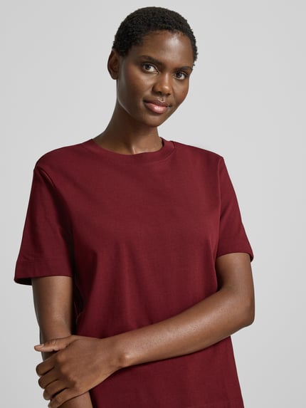 Kobiece modelka nosi Damski t-shirt Boxy Fit T-Shirt aus reiner Baumwolle Modell 'ESSENTIAL' od Selected w kolorze bordowym, gładka faktura, damski t-shirt, zbliżenie na górną część ciała, widok z przodu.