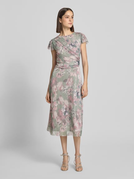Modelka nosi Schimmerndes Cocktailkleid mit Rundhalsausschnitt od Swing, połyskujący materiał z domieszką stretchu, krój taliowany, długość midi, kwiatowy wzór, szerokość w rozmiarze 36: 37 cm, długość pleców: 115 cm, długość rękawa: 8 cm, widok całej sylwetki z przodu.