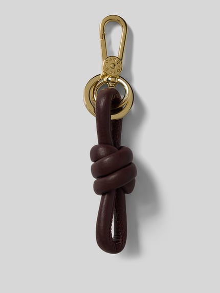 Productfoto, sleutelhanger met knoopdetail van Abro in donkerbruin leer met goudkleurige karabijnhaak en Label in reliëf