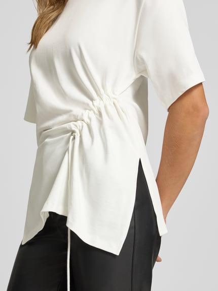 Frauenmodel trägt Longshirt mit Rundhalsausschnitt und Tunnelzug von Gina Tricot in Weiß, aus reiner Baumwolle, Nahaufnahme Oberkörper.