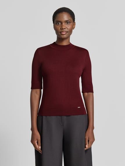 Vrouwenmodel draagt gebreid shirt uit Viscosemix met stretch, recht model, ronde hals, 1/2-mouwen, labeldetail van MORE, ruglengte maat 36: 55 cm, mouwlengte maat 36: 29 cm, Strickshirt aus Viskose-Mix met geribde ronde hals van MORE & MORE, voorkant full body shot.