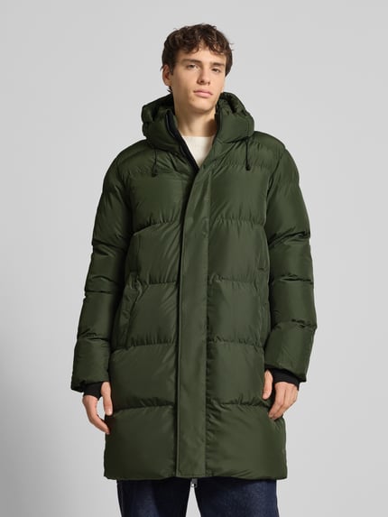 Mannenmodel draagt Steppmantel met Kapuze und Zweiwege-Reißverschluss van Superdry in donkergroen, rechte snit, met capuchon, elastische mouwboorden, zijzakken, vooraanzicht volledige lichaamsopname.