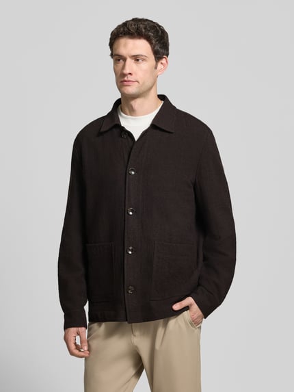 Männermodel trägt Blouson Modell 'Dellin' von STRELLSON in Unifarben mit Umlegekragen, Knopfleiste und Pattentaschen, Ganzkörperansicht von vorne.
