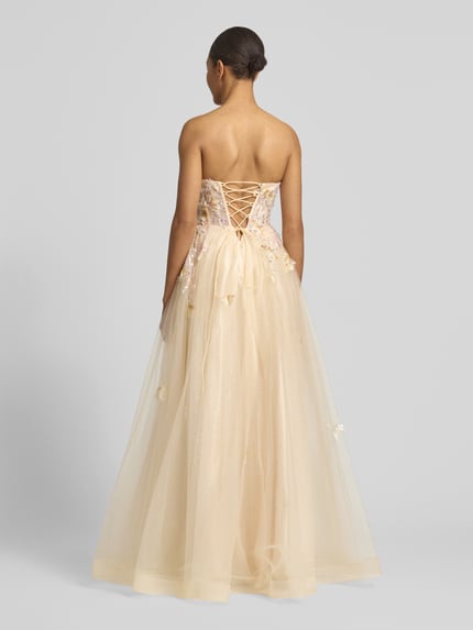 Frauenmodel trägt Abendkleid mit floralem Stitching von Unique, Glitzermesh, Tailliert, Pailettenbesatz, Schulterfrei, Rückenlänge 116 cm, Brustweite 33 cm, Ganzkörperansicht Rückansicht.