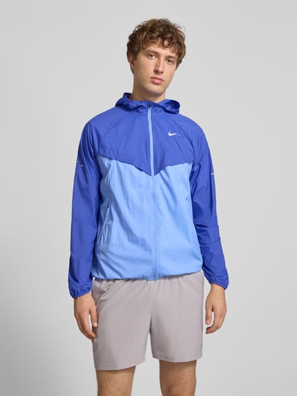 Männermodel trägt Trainingsjacke mit Logo-Print und Kapuze von NIKE TRAINING in Blau mit Reißverschluss, geradem Schnitt, Ganzkörperansicht von vorne.