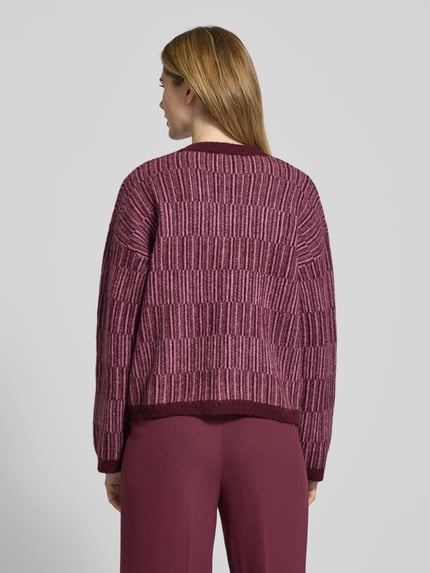 Frauenmodel trägt Relaxed Fit Strickpullover aus Woll-Mix mit Alpaka-Anteil Modell 'FALVA' von Selected Femme, bordeauxfarben mit Strukturmuster, gerippte Abschlüsse, Allover-Muster, Ganzkörperansicht Rückansicht.