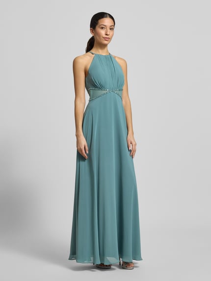 Modelka kobieca ma na sobie Regular Fit Abendkleid mit Ziersteinbesatz od Jake*s Cocktail, turkusowy, ozdobione kamieniami, krój regular fit, dopasowana talia, półprzezroczyste partie, dekolt typu halter, marszczenia, nieprzezroczysta podszewka, długość pleców w rozmiarze 36: 156 cm, szerokość w rozmiarze 36: 38 cm, widok całej sylwetki z przodu.