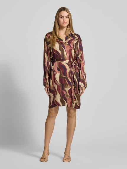 Frauenmodel trägt Minikleid aus Viskose mit Bindegürtel Modell 'Be44atricee' von ZABAIONE, abstraktes Muster, A-Linie, Ganzkörperansicht von vorne.