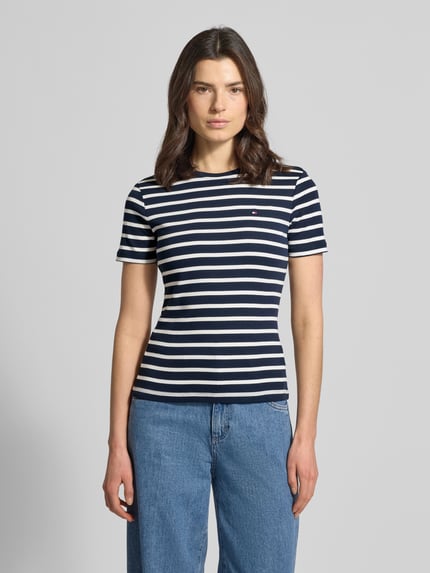 Frauenmodel trägt Slim Fit T-Shirt aus reiner Baumwolle von Tommy Hilfiger, Optik: Unifarben, Logo-Stitching, Rundhals, Kurzarm, Jersey, Ganzkörperansicht von vorne.