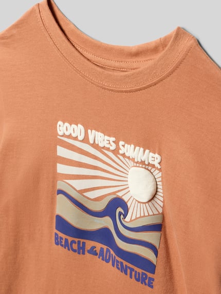 Produktfoto, T-Shirt mit Motiv-Print von Blue Seven, Kinder T-Shirt aus Reine Baumwolle, Regular-Fit, Rundhalsausschnitt, Rückenlänge 39 cm Größe 116, sandfarben mit blauem und weißem Print, wellige Formen, glatte Baumwoll-Textur.