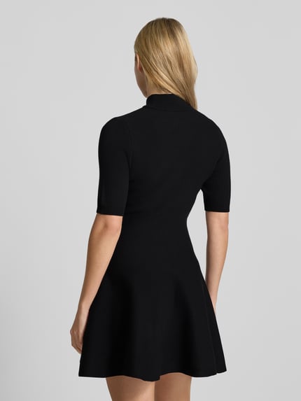 Frauenmodel trägt Minikleid aus Viskose-Mix mit Stehkragen von Apricot, schwarzer A-Linien-Schnitt, 1/2-Arm, Rückenansicht, Ganzkörperansicht Rückansicht.