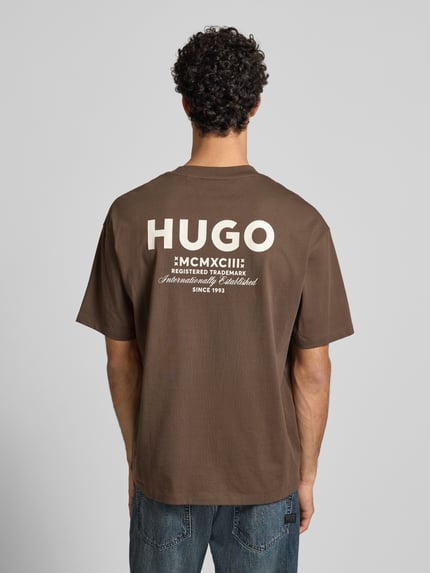 Mężczyzna nosi brązowy Oversized T-Shirt aus reiner Baumwolle Modell 'NALONO' od Hugo Blue, gładki jersey, nadruk z logo, widok z tyłu całej sylwetki.