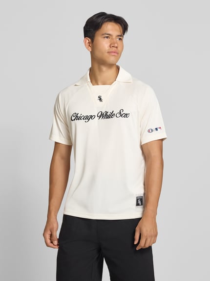 Männermodel trägt Relaxed Fit Poloshirt mit Logo-Stitching von Champion, cremefarben, schwarzer Schriftzug, Polokragen, kurzärmelig, Ganzkörperansicht von vorne, Rückenlänge bei Größe M 70 cm.