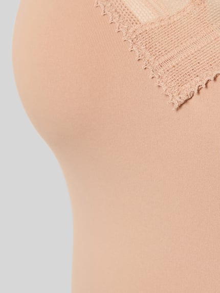 Mężczyzna model nosi Slim Fit Top mit Spitzenbesatz Modell 'Go Blush' od Sloggi, beżowy kolor, gładka faktura, detal góry, krój slim fit, z koronkowym wykończeniem, damski top, zdjęcie detailaufnahme.