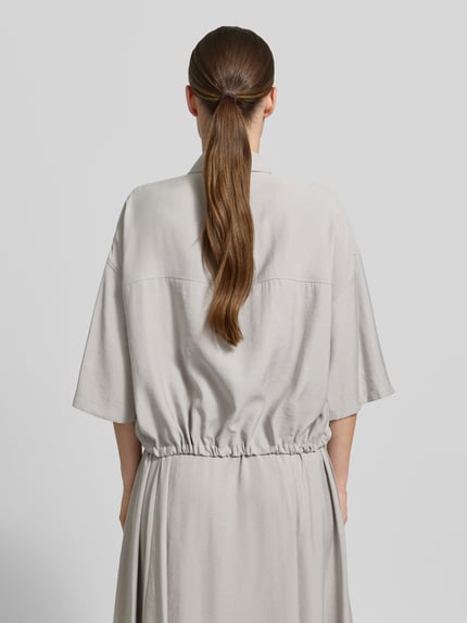 Vrouwenmodel draagt Boxy Fit blouse uit modalmix model 'LAINAY' van Drykorn, lichtgrijs met platte kraag, 3/4-mouw, tunnelkoord, ruglengte bij maat 36: 54 cm, mouwlengte bij maat 36: 27 cm, geheel van achteren gezien.