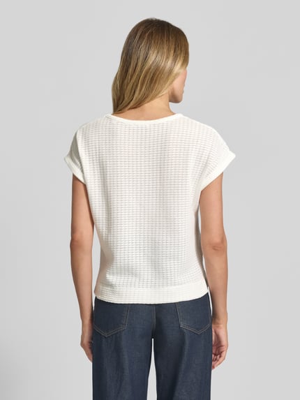 Modelka kobieca ma na sobie Strickshirt mit Rundhalsausschnitt Modell 'Sishell' od OPUS, biały, bawełniany melanż, krój regular fit, tył 55 cm w rozmiarze 36, tekstura dzianiny, całkowity widok z tyłu.