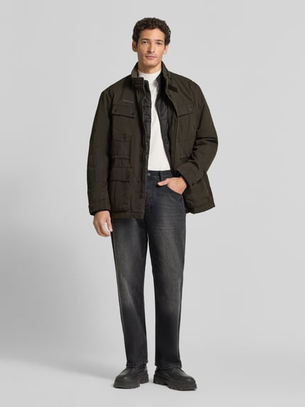 Männermodel trägt Jacke mit Stehkragen und Pattentaschen von camel active in Schwarz, Regular Fit, Ganzkörperansicht von vorne. Rückenlänge 79 cm, Schulterbreite 44 cm, Brustweite 65 cm, Ärmellänge 71 cm.