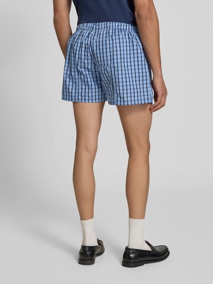 Männermodel trägt Boxershorts aus reiner Baumwolle von VETEMENTS, kariert, lockere Passform, elastischer Bund, Label-Patch, Ganzkörperansicht Rückansicht.