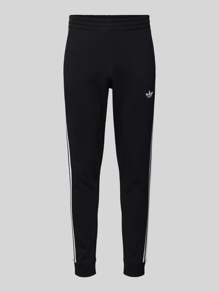 Produktfoto, Sweatpants met elastische tailleband van adidas Originals, zwart met witte strepen, los model, franjes aan de zakken, stretchmateriaal.