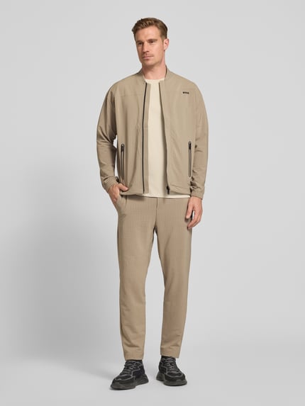 Männermodel trägt Tapered Fit Hose mit Waffelstrukturmuster Modell 'TERRACE' von BOSS Green, beige, Optik:Allover-Muster, Ganzkörperansicht von vorne.