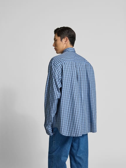 Männermodel trägt Relaxed Fit Freizeithemd aus Baumwolle von VETEMENTS, blau kariert, Langärmlig, Rückenlänge 84 cm, Ganzkörperansicht Rückansicht.