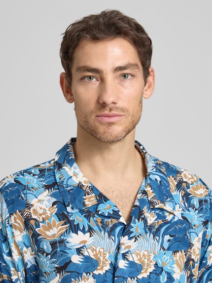 Męski model nosi Regular Fit Freizeithemd aus reiner Viskose Modell 'BEACH' od BOSS, niebieski wzór allover, krój regular fit, kołnierz rewersowy, krótki rękaw, widok z przodu, zbliżenie na górną część ciała.